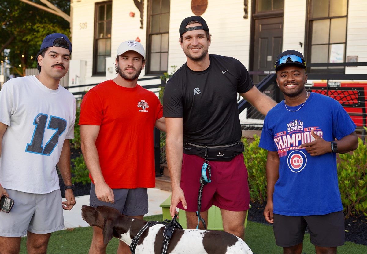 Four runners smiling with a dog before a Sunday run in downtown Woodstock