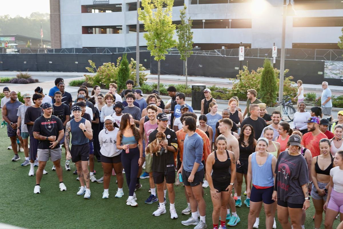 A large group of Flyte Run Club runners gathered on the turf in downtown Woodstock before a Sunday run